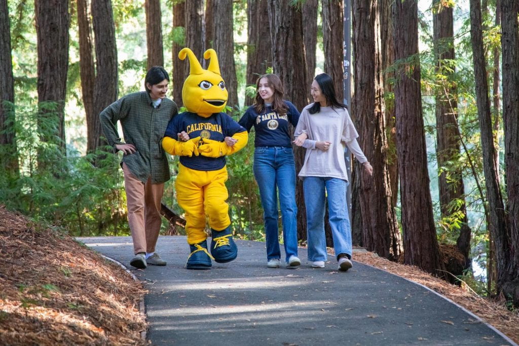 UCSC Sammy mascot walking in the woods with students.