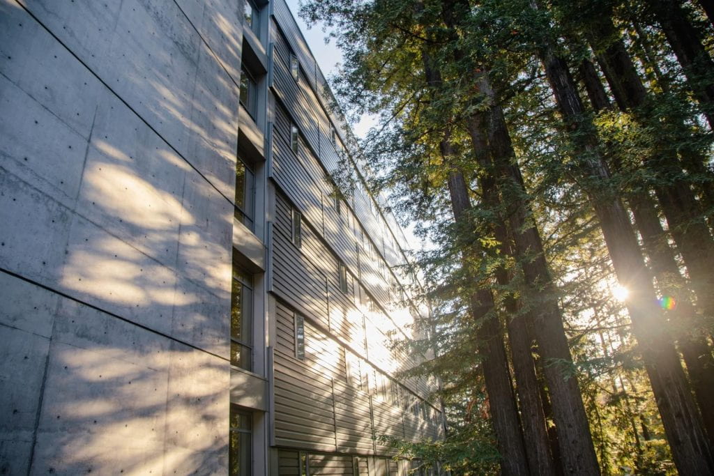 The UCSC Humanities building mottled in sunlight that is coming through the trees on campus.